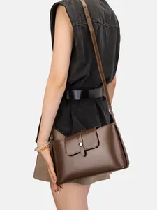 Minimalistische dunkelbraune Leder-Schultertasche getragen von einem Modell in Schwarz