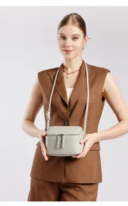 Gros plan d'un sac bandoulière en cuir grainé gris clair avec double fermeture éclair
