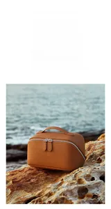 Close-up of pebble grain leather texture and dual zipper detail on brown cosmetic bag