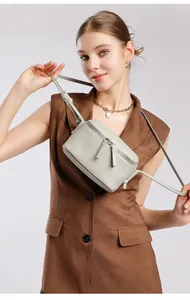 Gros plan du sac bandoulière en cuir grainé gris clair avec double fermeture éclair métal