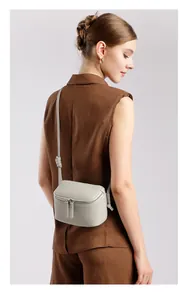 Sac bandoulière minimaliste en cuir gris clair porté par un mannequin de profil