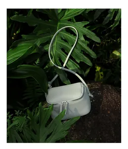 Détail d'un sac bandoulière en cuir bleu clair avec double fermeture éclair sur roche