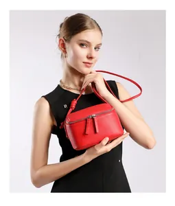 Gros plan du sac bandoulière rouge en cuir grainé avec double fermeture éclair sur mannequin