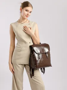Zaino grande in pelle cerata marrone scuro con fibbie argentate indossato da un modello