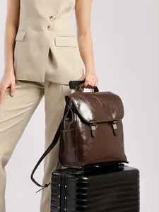 Zaino vintage in pelle cerata marrone con fibbie in metallo su una valigia nera