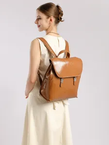 Zaino grande in pelle cerata marrone con chiusura a patta indossato da una modella