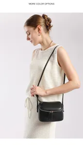 Détail d'un sac bandoulière en cuir grainé noir porté avec une tenue en tricot blanc