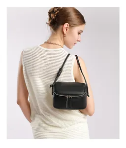 Détail d'un sac bandoulière en cuir noir grainé avec fermetures éclair argentées