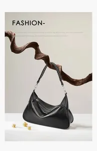 Dettaglio del manico in pelle intrecciata e cerniera metallica su borsa tote nera