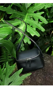 Détail d'un sac bandoulière en cuir grainé noir avec double fermeture éclair supérieure