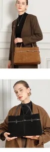 Detail of matte suede tote bag with leather straps and metal buckles in brown and black