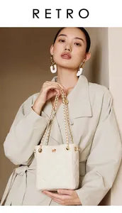 Detail of quilted bucket bag with gold chain strap and floral buckle on cream leather