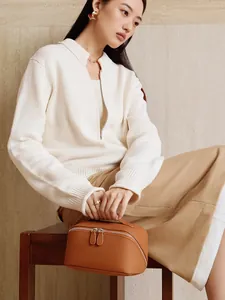 Elegant brown pebble grain leather cosmetic bag shown in a lifestyle travel setting