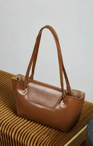 Detail of khaki leather crossbody bag showing semi-flap design and metal rivets