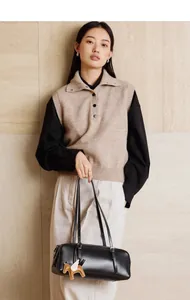 Bolso bowling de cuero negro minimalista con colgante de caballo, llevado por modelo