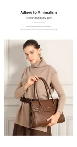 Dettaglio di una borsa tote in pelle marrone con placca in metallo e fibbie laterali
