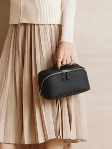 Minimalist black pebble grain leather cosmetic bag with top handle and metal zippers