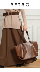 Detail of genuine brown leather tote bag showing handle texture and hangtag