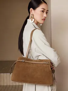 Brown suede leather tote bag with metallic buckle and shoulder strap on a model