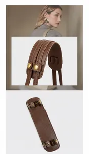 Macro view of wide brown leather shoulder strap with vintage metal buckle and edge stitching