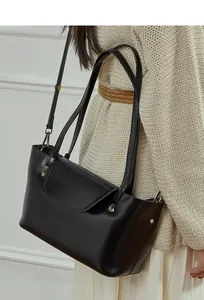 Detail of minimalist black crossbody bag with gold studs on beige knit sweater