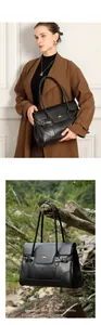Dettaglio della borsa tote in pelle nera con doppi manici e logo dorato elegante