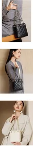 Detail of quilted bucket bag with gold chain strap and floral metal emblem for women