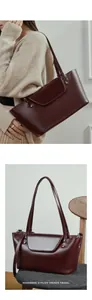 Detail of burgundy leather tote bag with gold buckles and dual shoulder straps