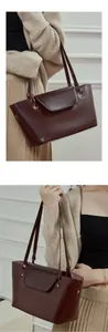 Detail view of burgundy leather tote bag with polished finish and metal rivet decoration