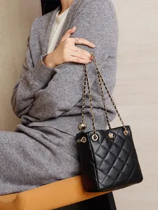 Black quilted leather shoulder bag with gold chain and flower logo on model