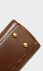 Detail of genuine leather bag base with anti-wear gold metal studs and fine stitching