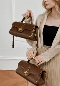 Detail view of a vintage brown leather handbag with gold metal lock and removable strap