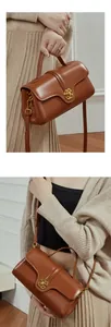Detailed view of dark brown leather bag with a vintage gold hollow clasp and top handle
