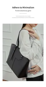 Detail of minimalist black leather tote bag featuring vertical stitching and metal hardware