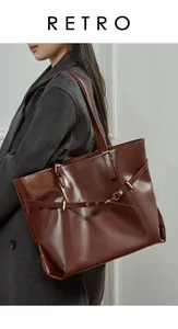 Detail view of large dark brown leather tote bag showing golden buckle and shoulder straps