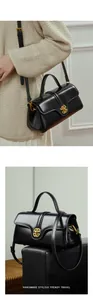 Detailed close-up of glossy black leather handbag with round golden metal lock buckle