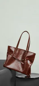 Detailed macro view of brown vintage leather tote bag with gold buckle and smooth texture