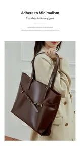 Detailed view of dark brown leather tote with metallic eyelets and adjustable shoulder strap