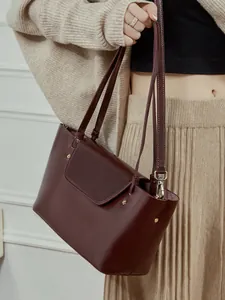 Elegant burgundy leather crossbody bag with gold rivet accents and spacious interior