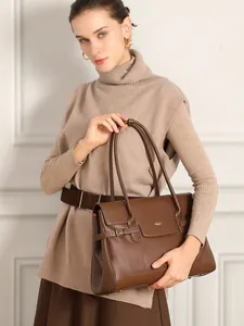 Borsa tote classica in pelle marrone scuro con patta tenuta da una modella in maglieria