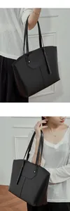 Close-up of a premium black leather tote bag showing vertical stitching and glossy finish