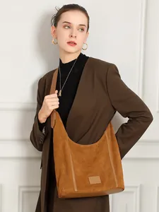 Sac hobo en cuir dépoli marron porté par un mannequin avec une tenue élégante