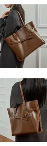Close-up showing the premium leather texture and metal buckle of the brown tote bag