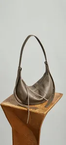 Detail of taupe leather half-moon shoulder bag with adjustable strap and smooth grain texture