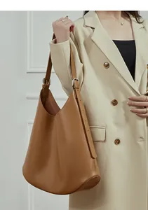 Detailed view of caramel brown leather hobo bag worn with a white blazer for elegant style