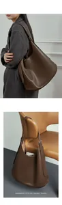 Detail of a dark brown hobo shoulder bag shown on a model and hanging on a modern chair