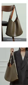 Close-up of minimalist leather shoulder bag detail with adjustable strap and silver buckle