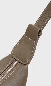 Close-up of taupe lychee leather texture with white contrast stitching and silver zipper