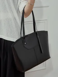 Minimalist black vegetable-tanned leather tote bag with silver rivets for women
