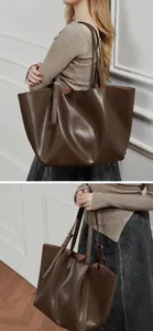Detail view of large brown faux leather tote bag with smooth texture and long shoulder strap